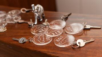 A wooden surface with keys and keychains, some with engraved numbers and text.