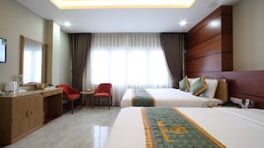 A hotel room with two beds, a desk with a chair, a mirror, and a window with curtains. - Silk Hotel (Ho Chi Minh City)