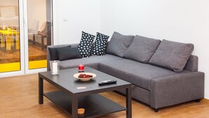 A modern living room with a grey sofa, a black coffee table, and a bowl of fruit. - Glyfada Square Modern And Cozy Apartment (Glyfada)