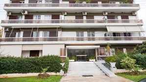 A multi-story residential building with balconies, air conditioning units, and a central entrance with steps. - Glyfada Square Modern And Cozy Apartment (Glyfada)