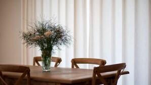 Una mesa de madera para comer con un florero en el centro, rodeada por cuatro sillas de madera.