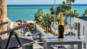 Ein Balkon mit Tisch, zwei Weingläsern und einer Champagnerflasche.