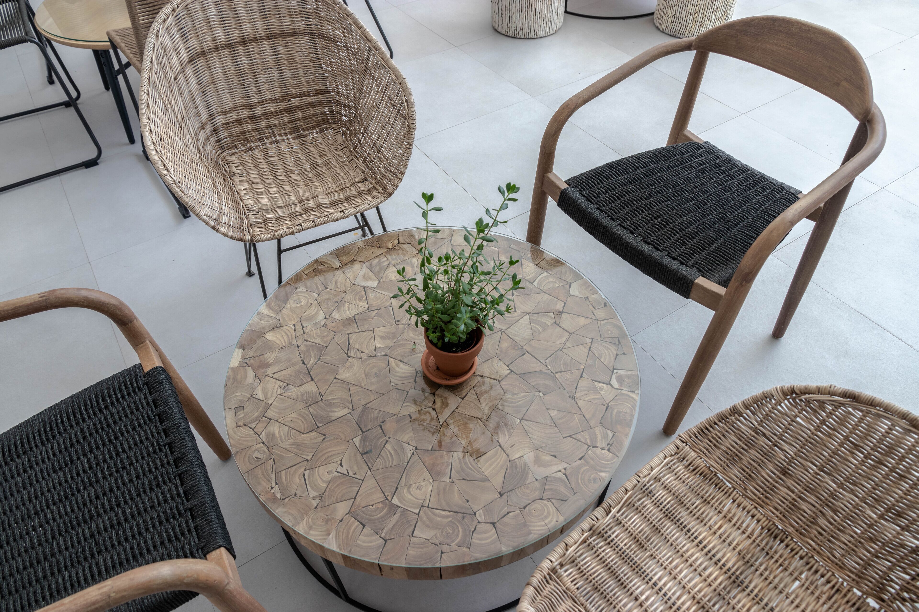 A round table with a mosaic top surrounded by wicker chairs with black cushions.