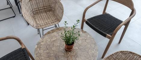 A round table with a mosaic top surrounded by wicker chairs with black cushions.