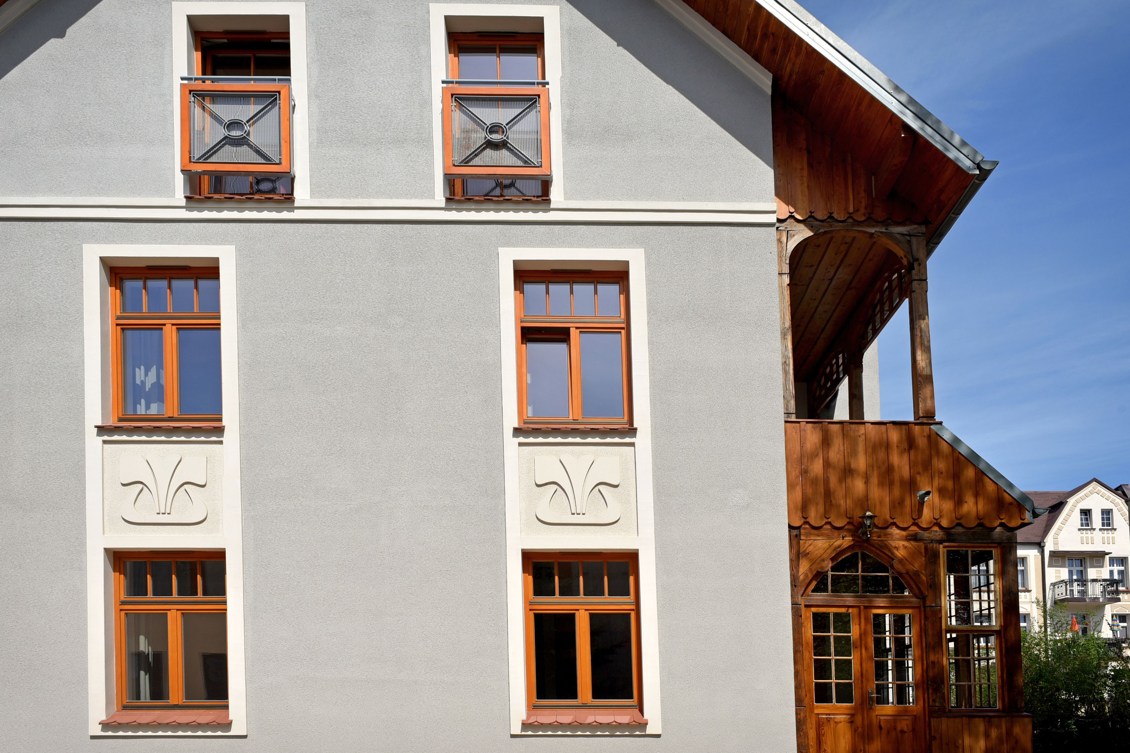 A building with multiple windows, some with shutters, and a wooden structure with a sloped roof.