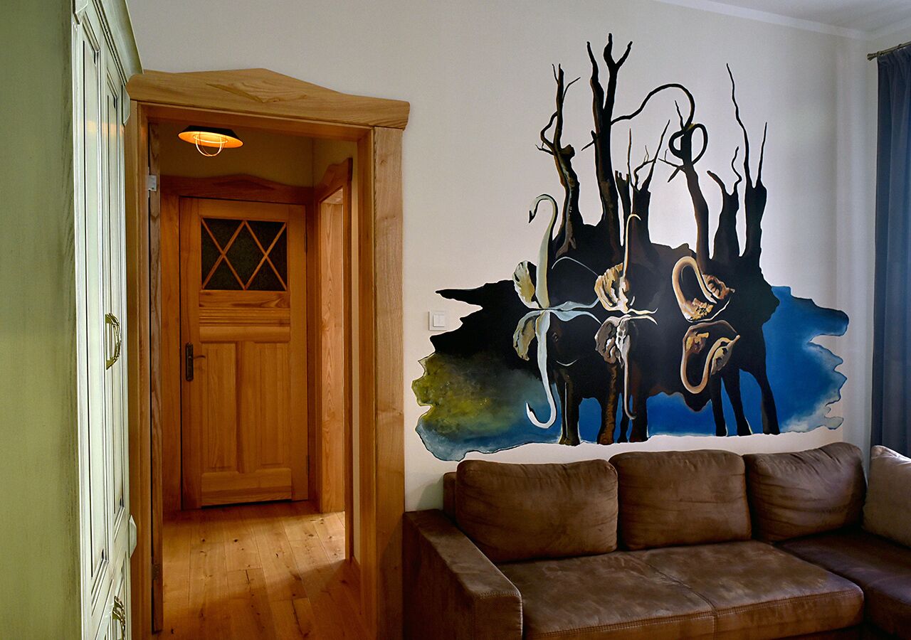 A wooden door with a diamond pattern, a brown leather sofa, and a wall mural of a forest scene with trees and animals.