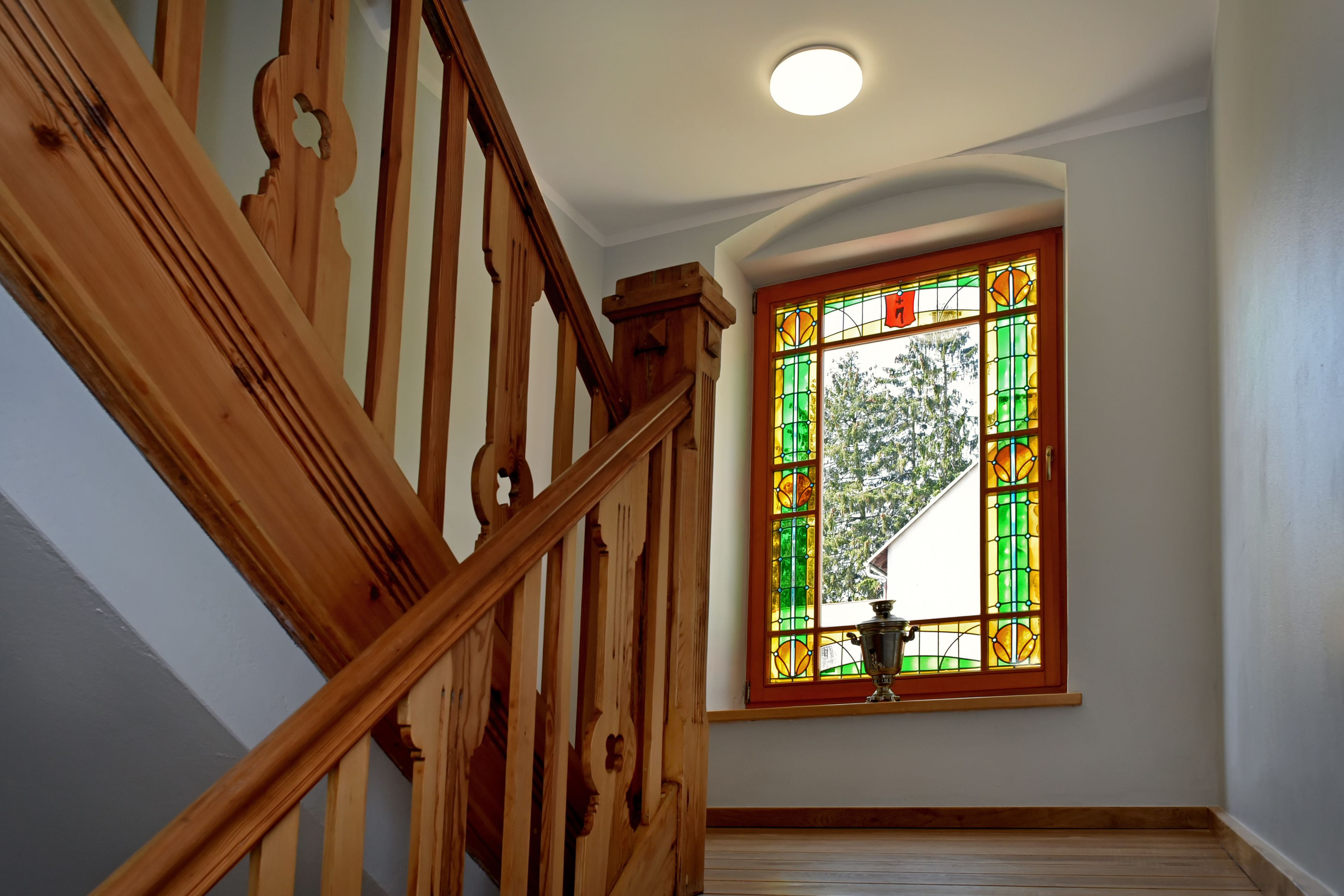 A wooden staircase with a stained glass window above it.