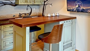 Una cocina con una isla de madera, taburetes de bar y una lámpara colgante.