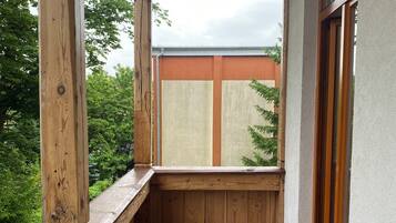 Un balcone in legno con pavimento piastrellato e vista sul verde.