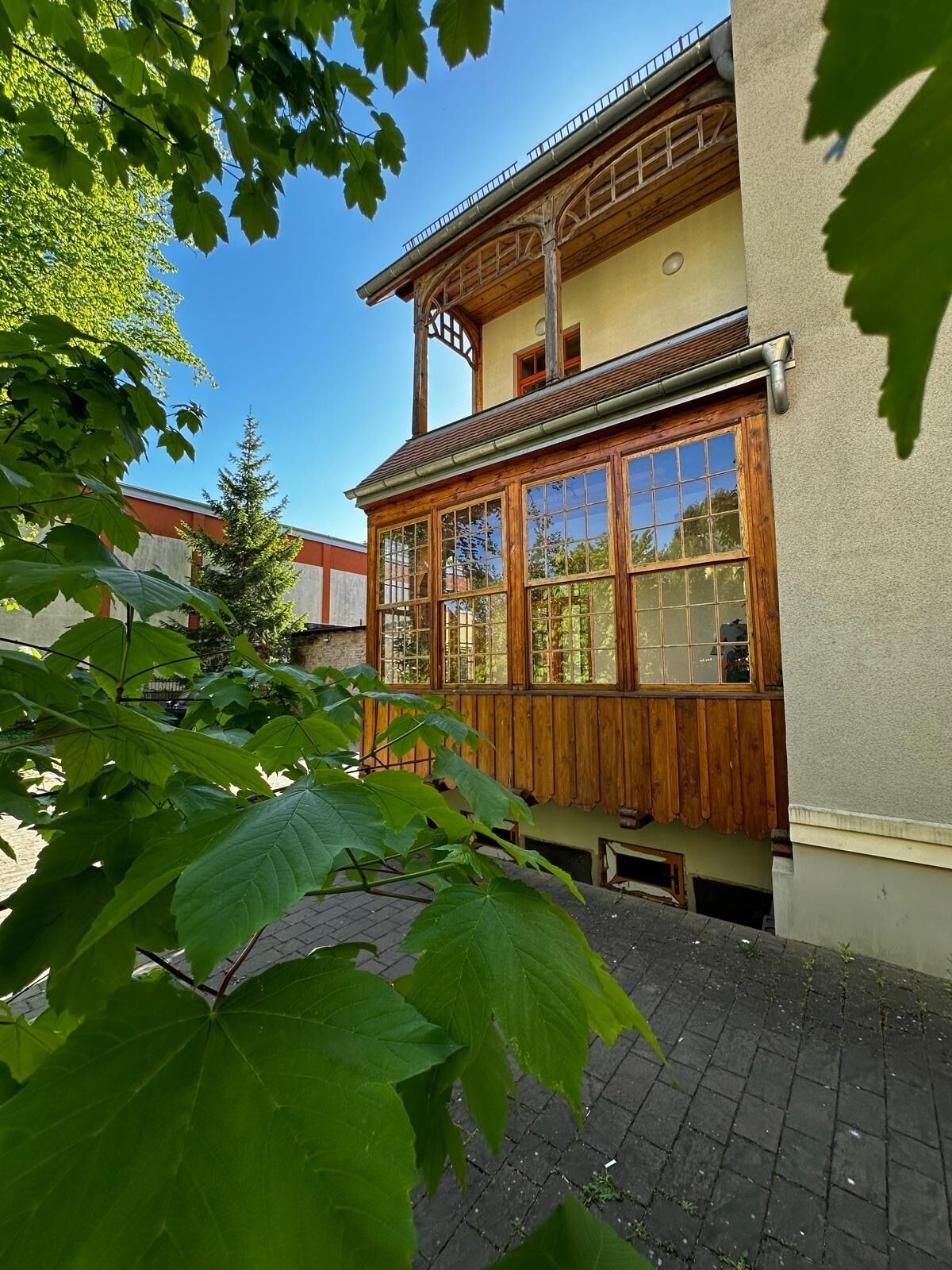 A two-story building with large windows and a wooden balcony.
