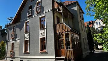 Un edificio de dos pisos con fachada gris, varias ventanas y un balcón de madera.