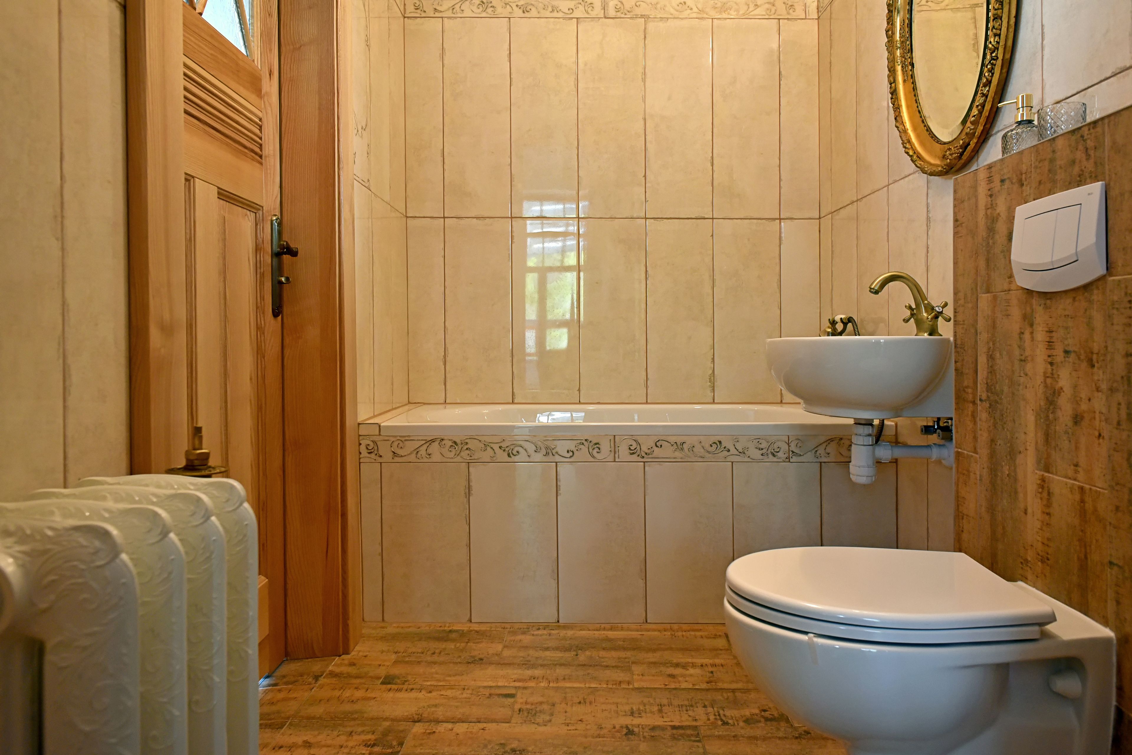 A bathroom with a wooden door, a white toilet, a sink, and a mirror.
