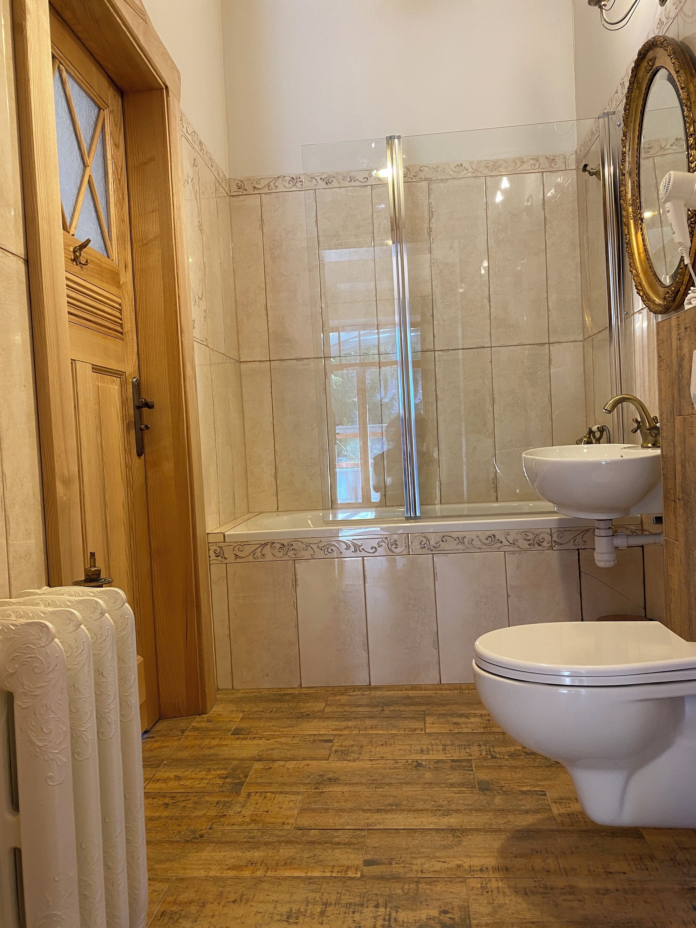 A bathroom with a wooden door, a bathtub, a toilet, and a sink.