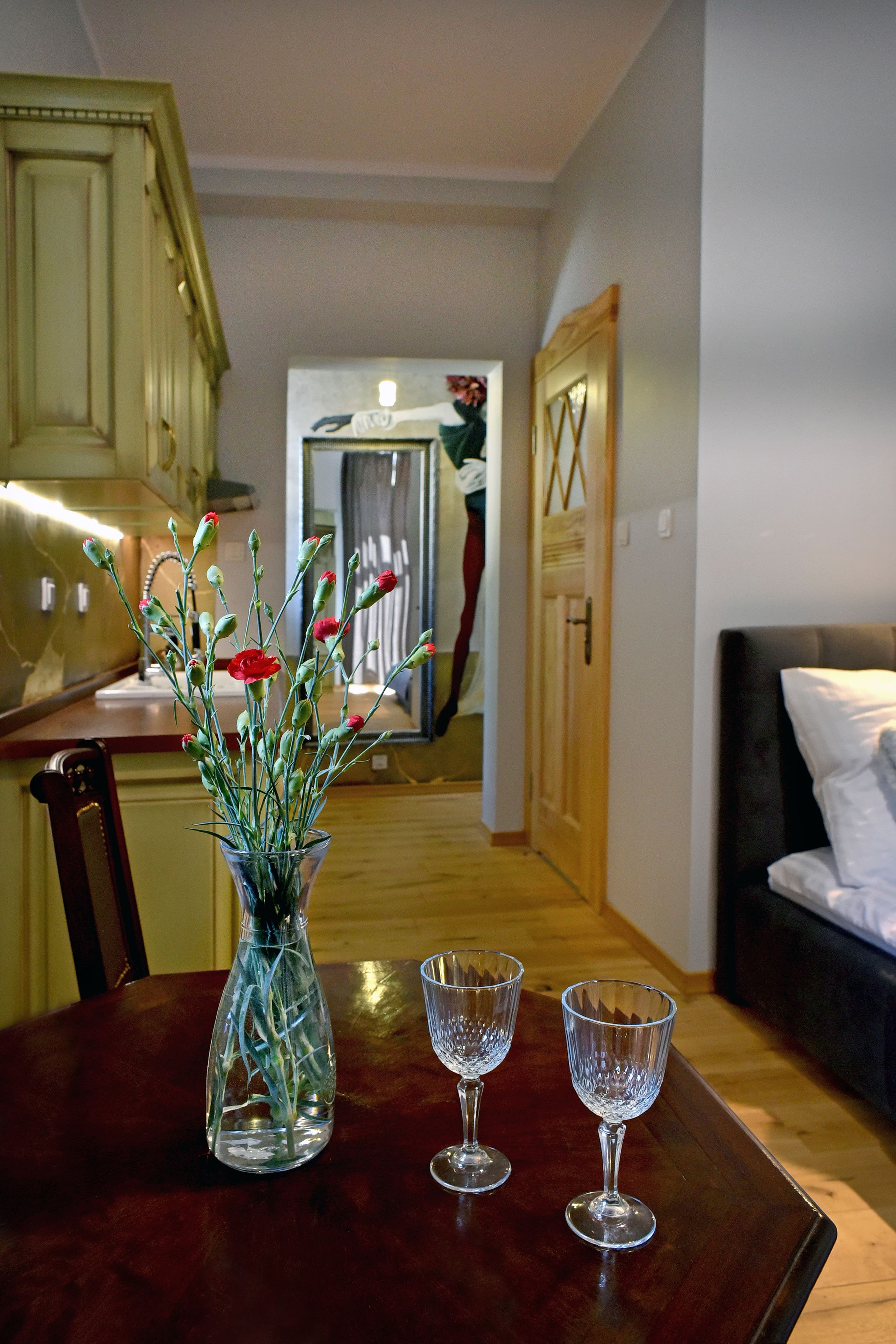 A dining table with a vase of flowers and two wine glasses.