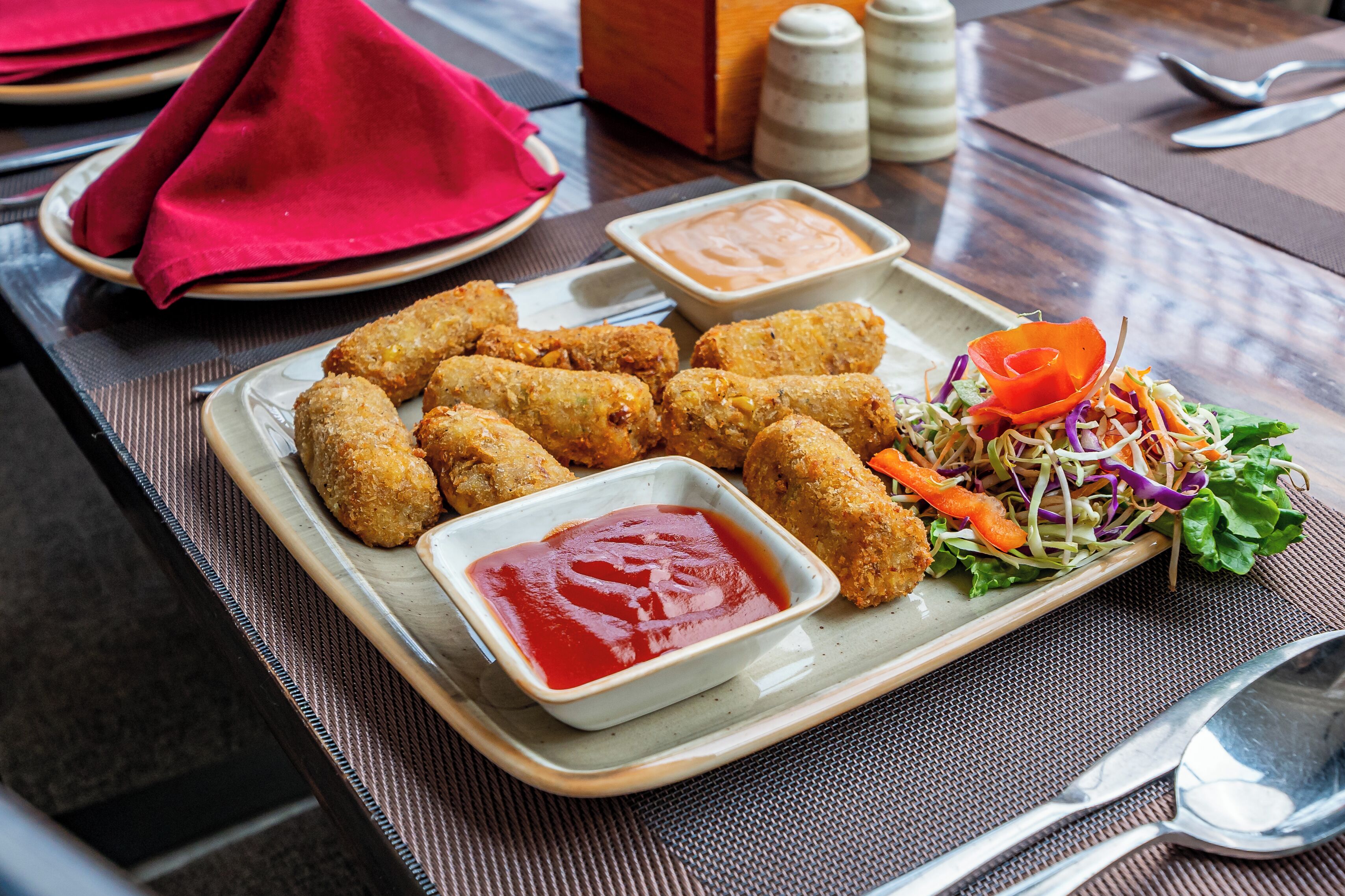 Une assiette de fritures accompagnée d’une salade et de deux sauces pour tremper.