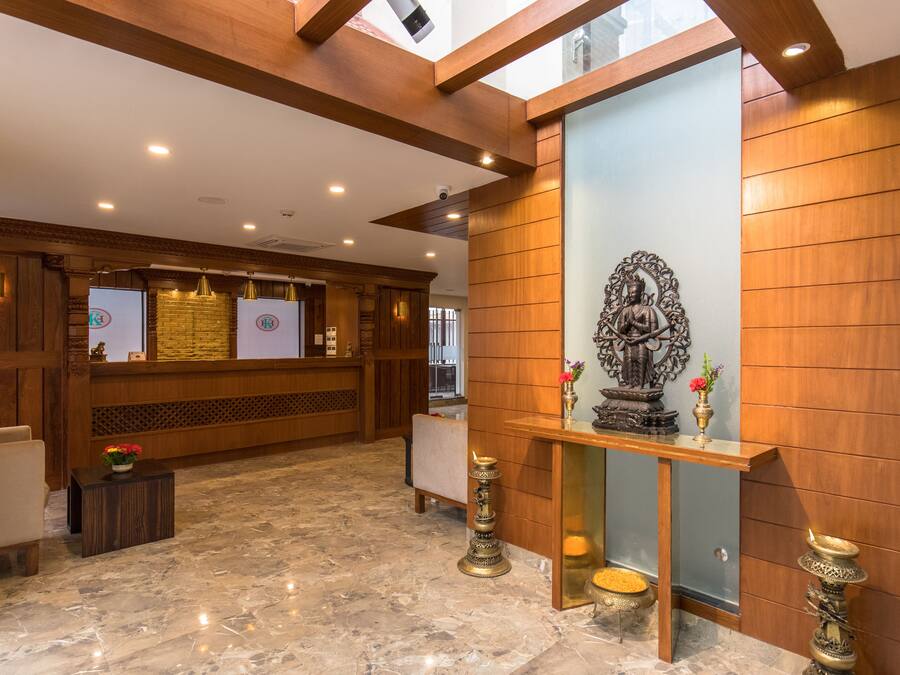 A reception area with a marble floor, wooden reception desk, and a statue on a pedestal.