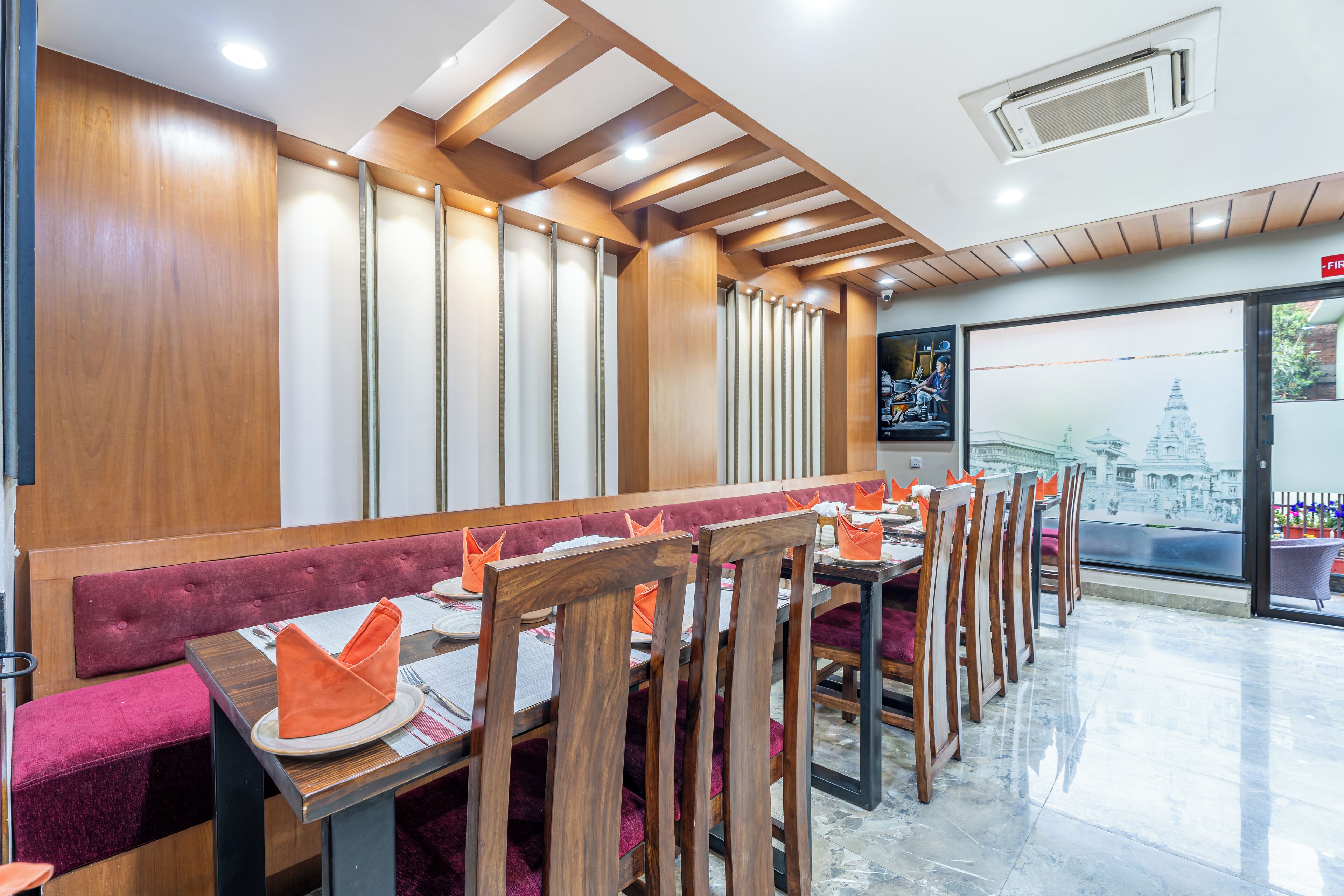 Un restaurante con paneles de madera, asientos acolchados y vista a un templo a través del ventanal.