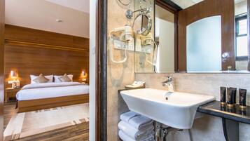 A hotel room with a bed, a bathroom with a sink and mirror, and a nightstand with a lamp.