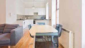 A modern kitchen with white cabinets, a wooden countertop, and a dining area with a table and chairs. - The Enya Suite - hiphipstay (Dublin)