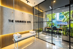 A modern hotel lobby with a reception desk, seating area, and large windows offering a view of the city. - The Hammock Hotel Fine Arts Museum (Ho Chi Minh City)