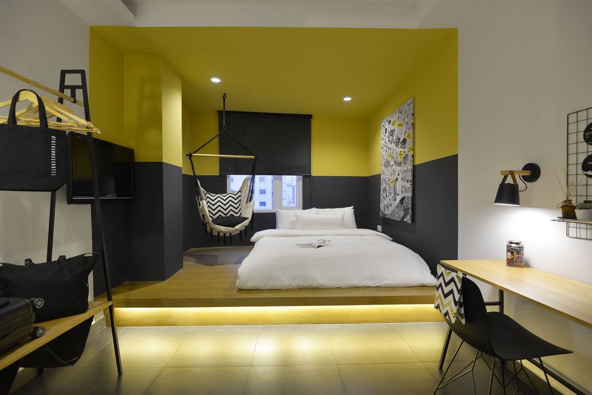 A modern hotel room with a bed, a desk, and a hanging chair.