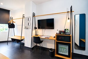 Ett modernt hotellrum med skrivbord, stol, tv och en minibar.