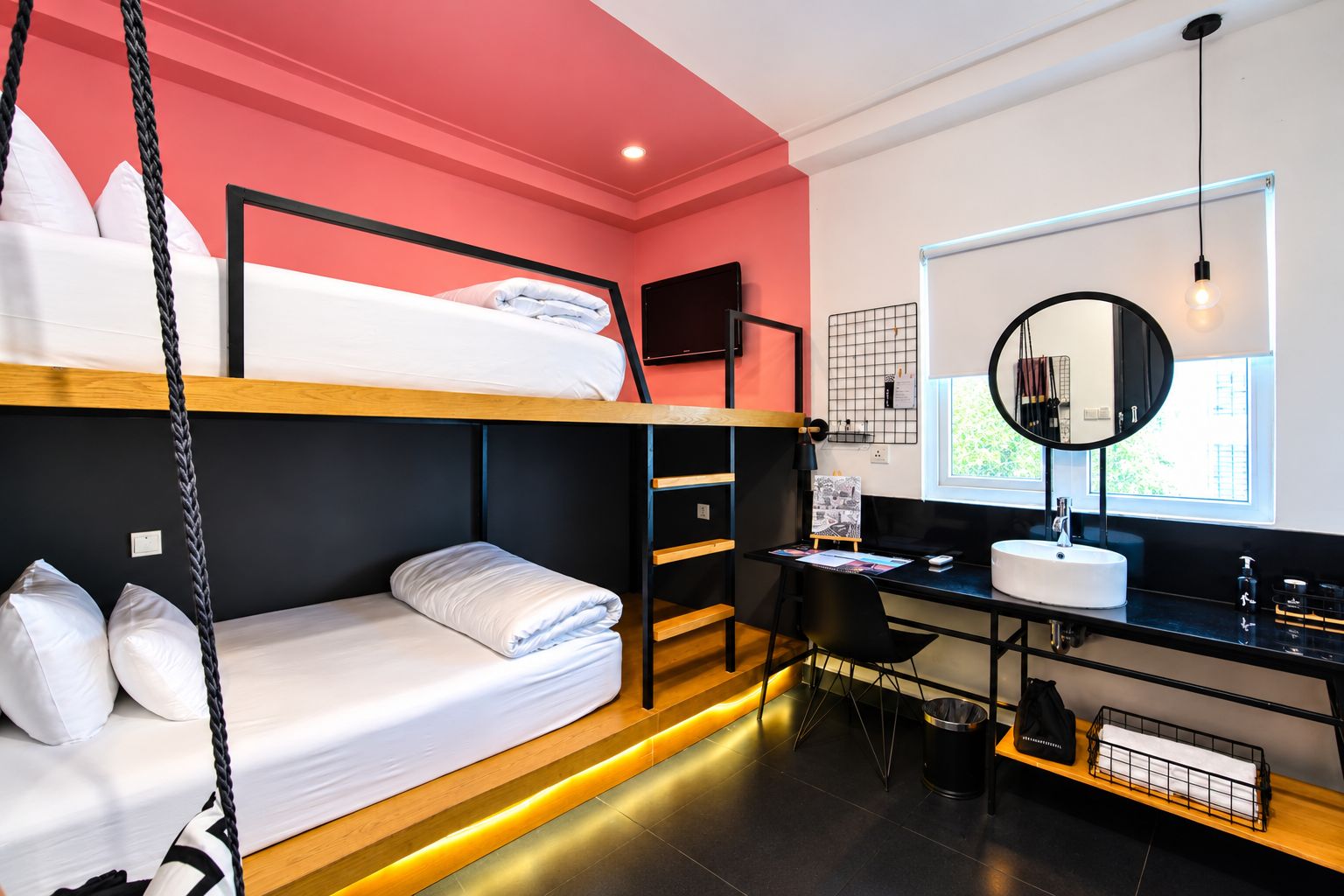 Habitación con literas, escritorio, espejo y ventana.