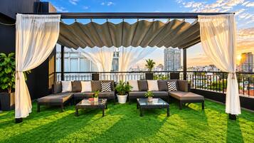 Terraço no telhado com área de estar, grama sintética verde e vista para o horizonte da cidade.