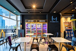 Un moderno hall de hotel con asientos, una máquina expendedora y vistas a la ciudad.