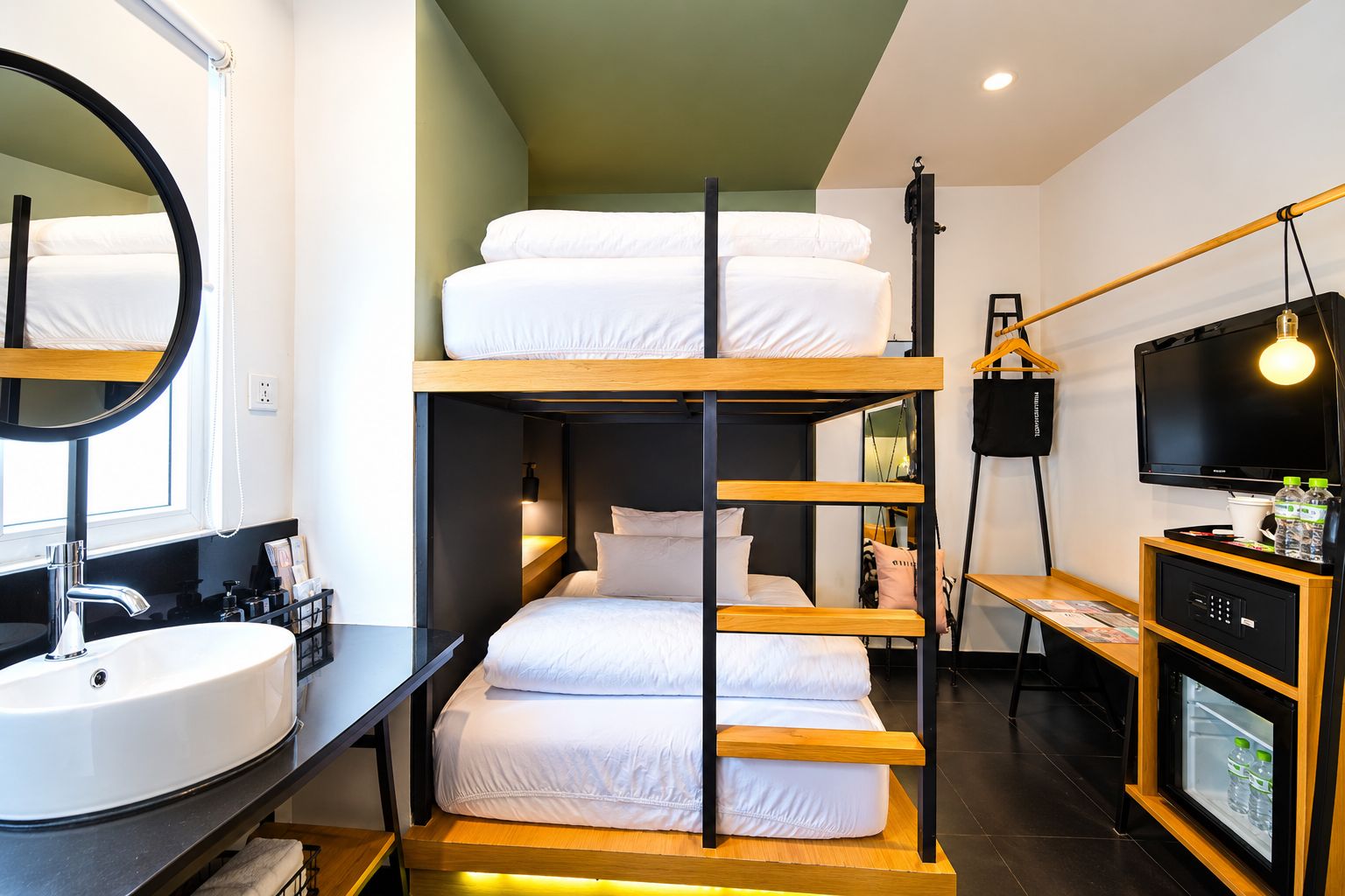 A bunk bed room with a sink, mirror, and TV.