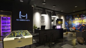 A modern hotel lobby with a foosball table, bar area, and a vibrant mural. - The Hammock Hotel Fine Arts Museum (Ho Chi Minh City)