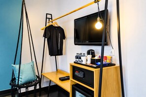 Una habitación de hotel moderna con una silla colgante, un escritorio con una cafetera, un televisor y un control remoto.