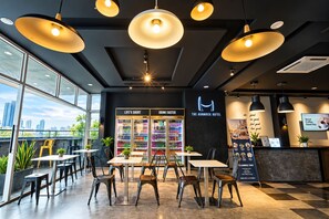 A modern hotel lobby with a city view, seating area, and a reception desk.