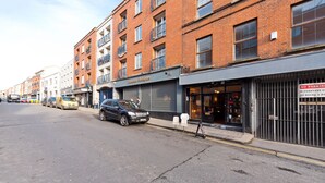 Et gadesyn med en række bygninger, heriblandt en butik med lukket markise og et skilt, der angiver parkeringsforbud.