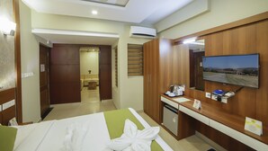 A hotel room with a bed, a desk with a television, a small kitchenette, and a bathroom. - Hotel Sreepathy Indraprastha (Chavakkad)