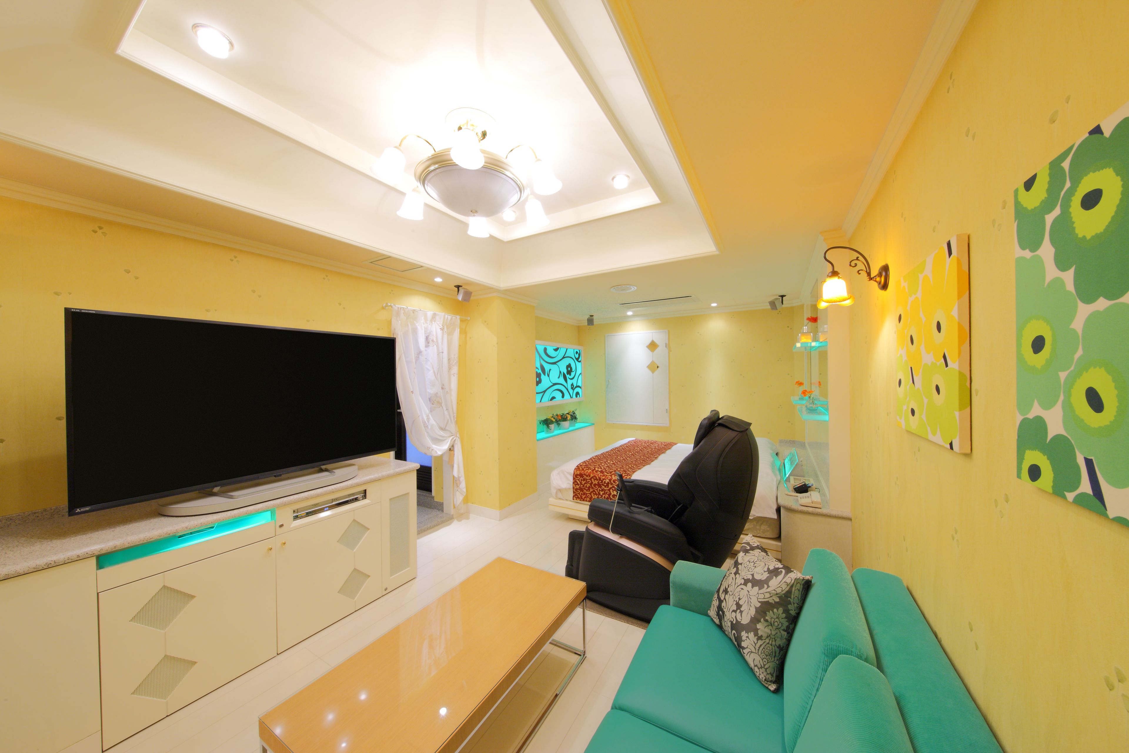 A modern living room with a flat-screen TV, a sofa, a massage chair, and a dining area.