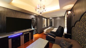 A modern living room with a flat-screen TV, a sofa, a chair, and a chandelier. - Hotel Cherena - Adult Only (Kunitachi)