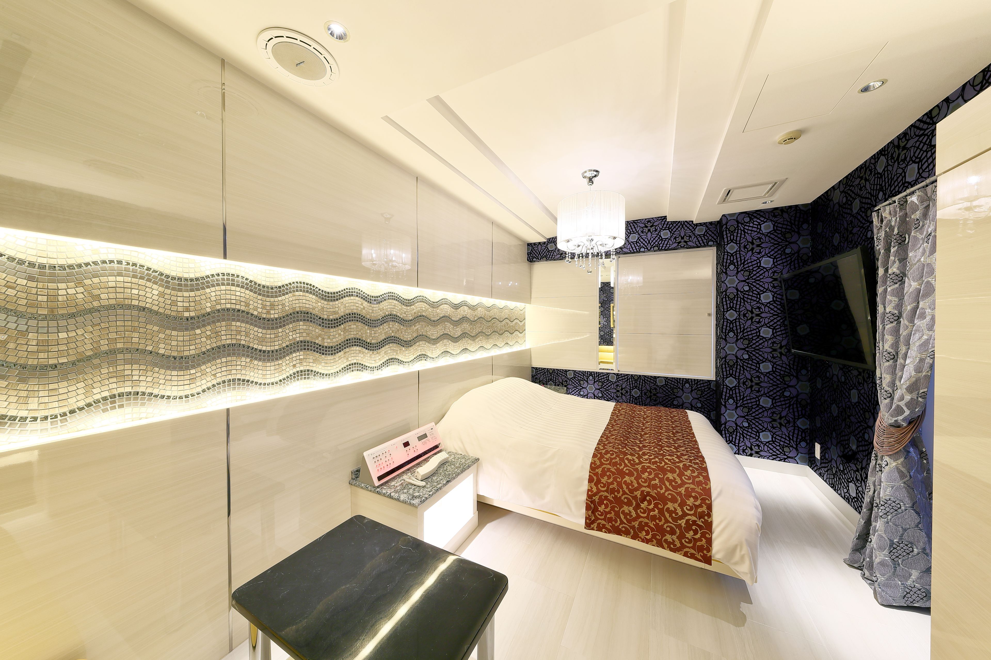 A modern bedroom with a bed, bedside table, and a decorative wall.