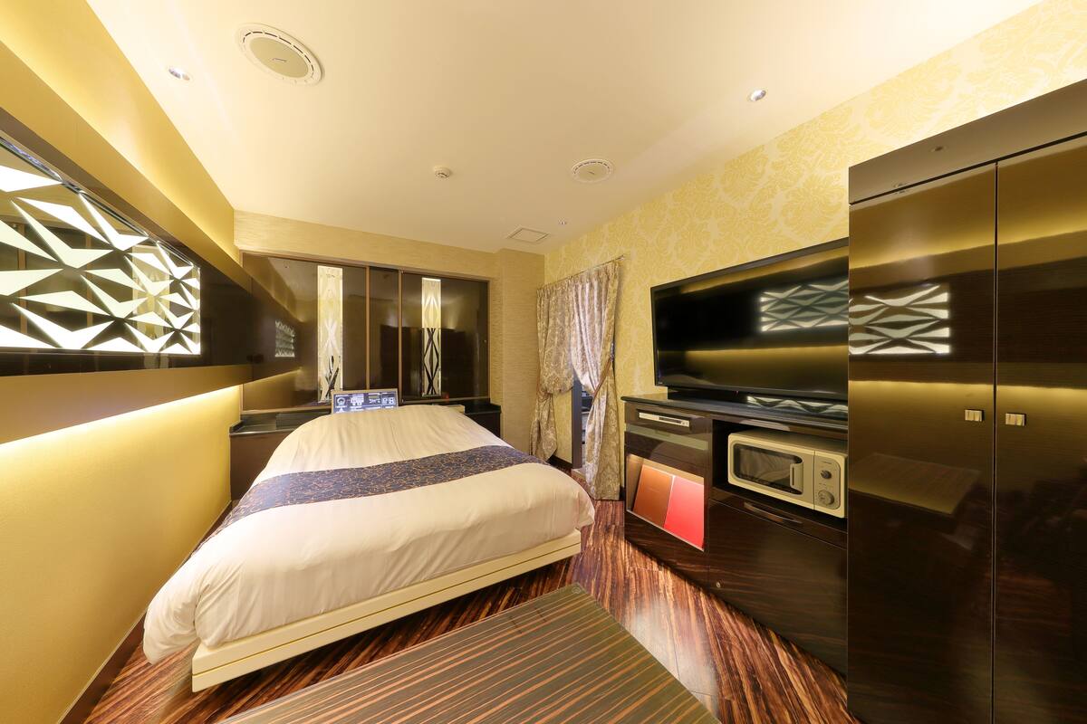 A hotel room with a bed, a TV, a microwave, and a wardrobe.