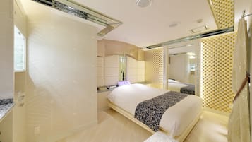 Een moderne slaapkamer met een groot bed, een nachtkastje en een spiegel.