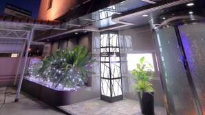A modern building with a glass facade and a rooftop garden with plants. - Hotel Cherena - Adult Only (Kunitachi)