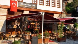 A traditional Turkish restaurant with outdoor seating, a flag, and a signboard. - Kuscu Han Otel (Safranbolu)