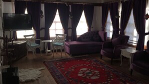 A living room with a sofa, chairs, a TV, and a patterned rug. - Kuscu Han Otel (Safranbolu)