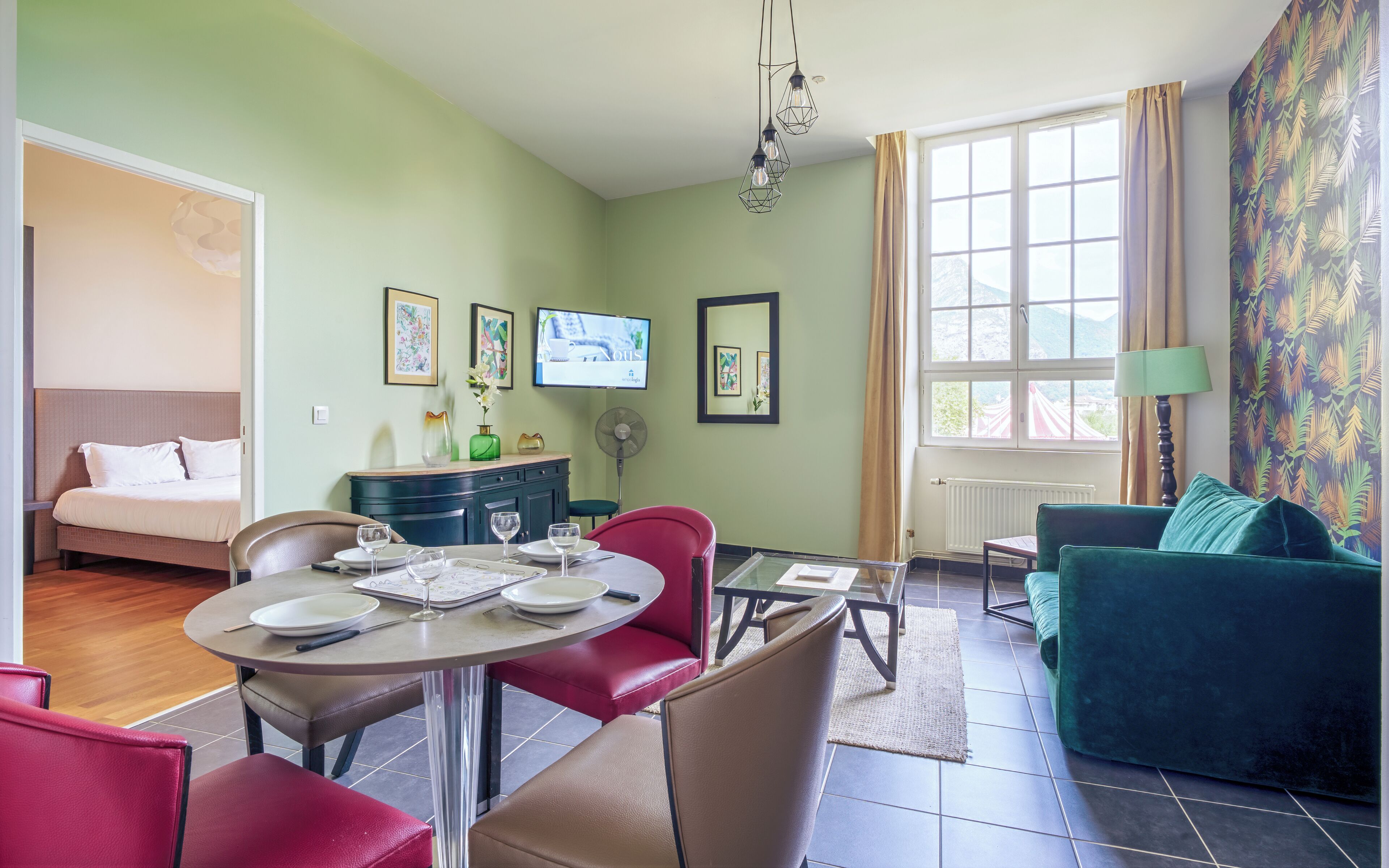 Una sala de estar con comedor, sofá, televisión y obras de arte en las paredes.