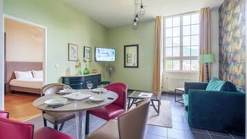 Una sala de estar con comedor, sofá, televisión y obras de arte en las paredes.
