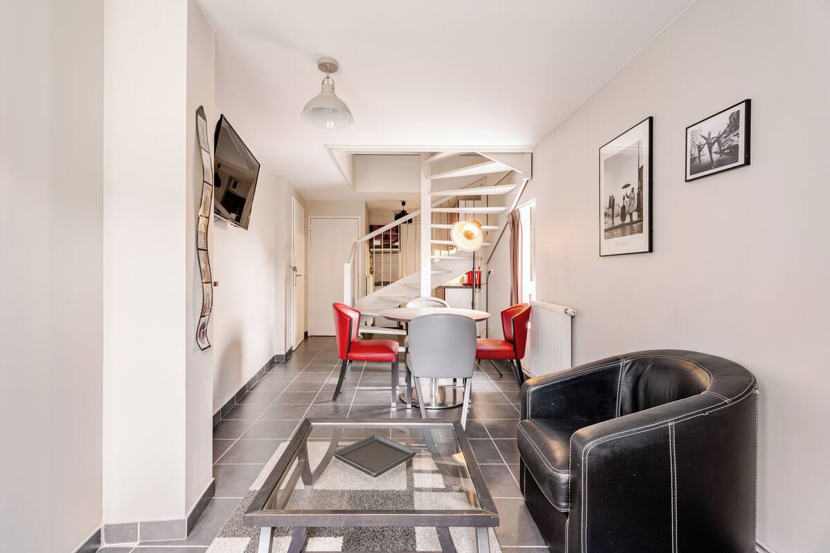 Um interior moderno com escada, área de jantar e um sofá de couro preto.