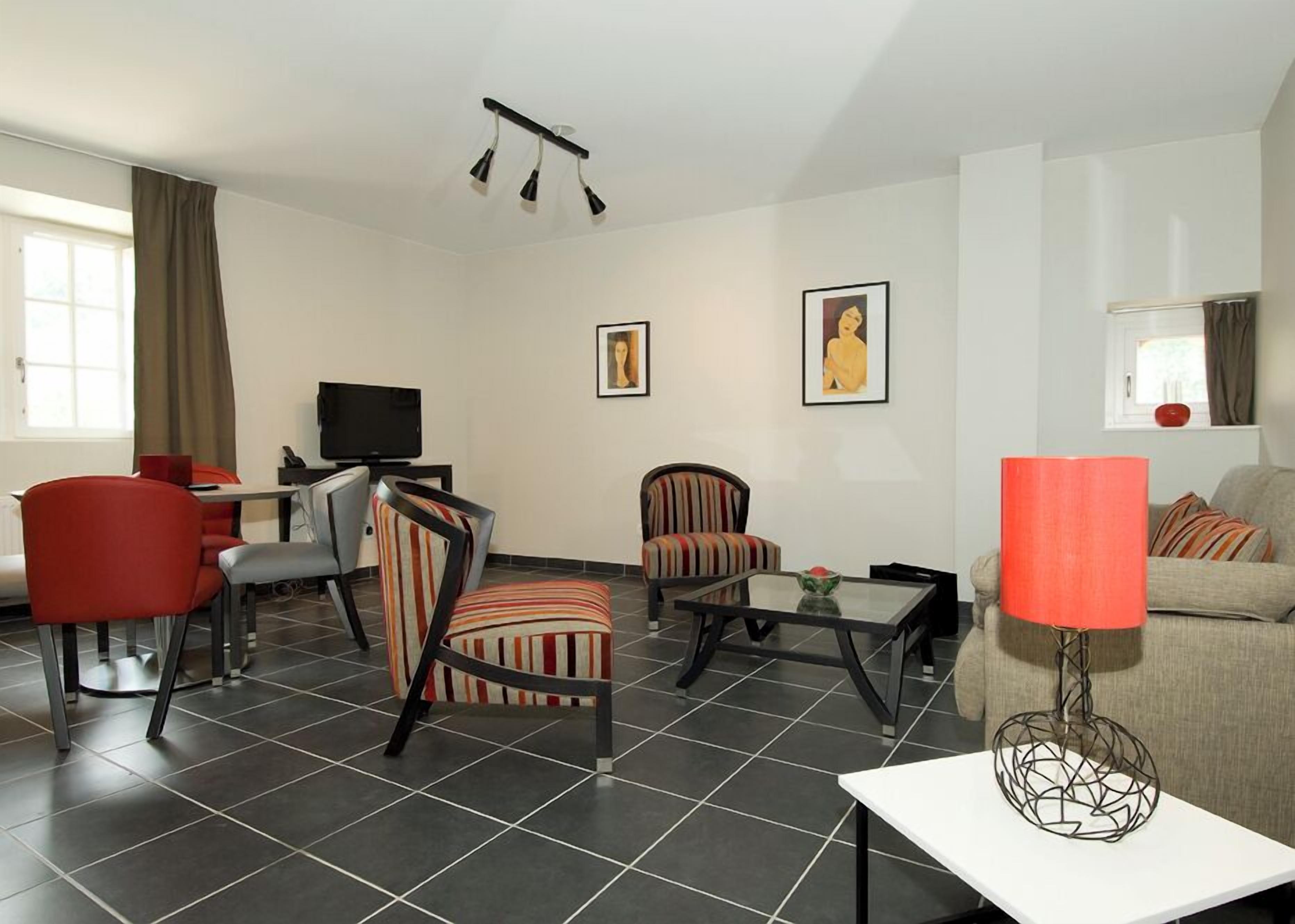 Una sala de estar moderna con un televisor de pantalla plana, sillones a rayas, un sofá rojo y una mesa de centro.
