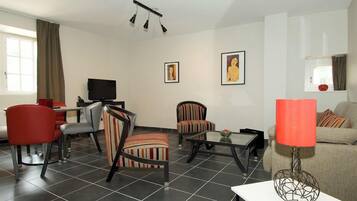 Una sala de estar moderna con un televisor de pantalla plana, sillones a rayas, un sofá rojo y una mesa de centro.