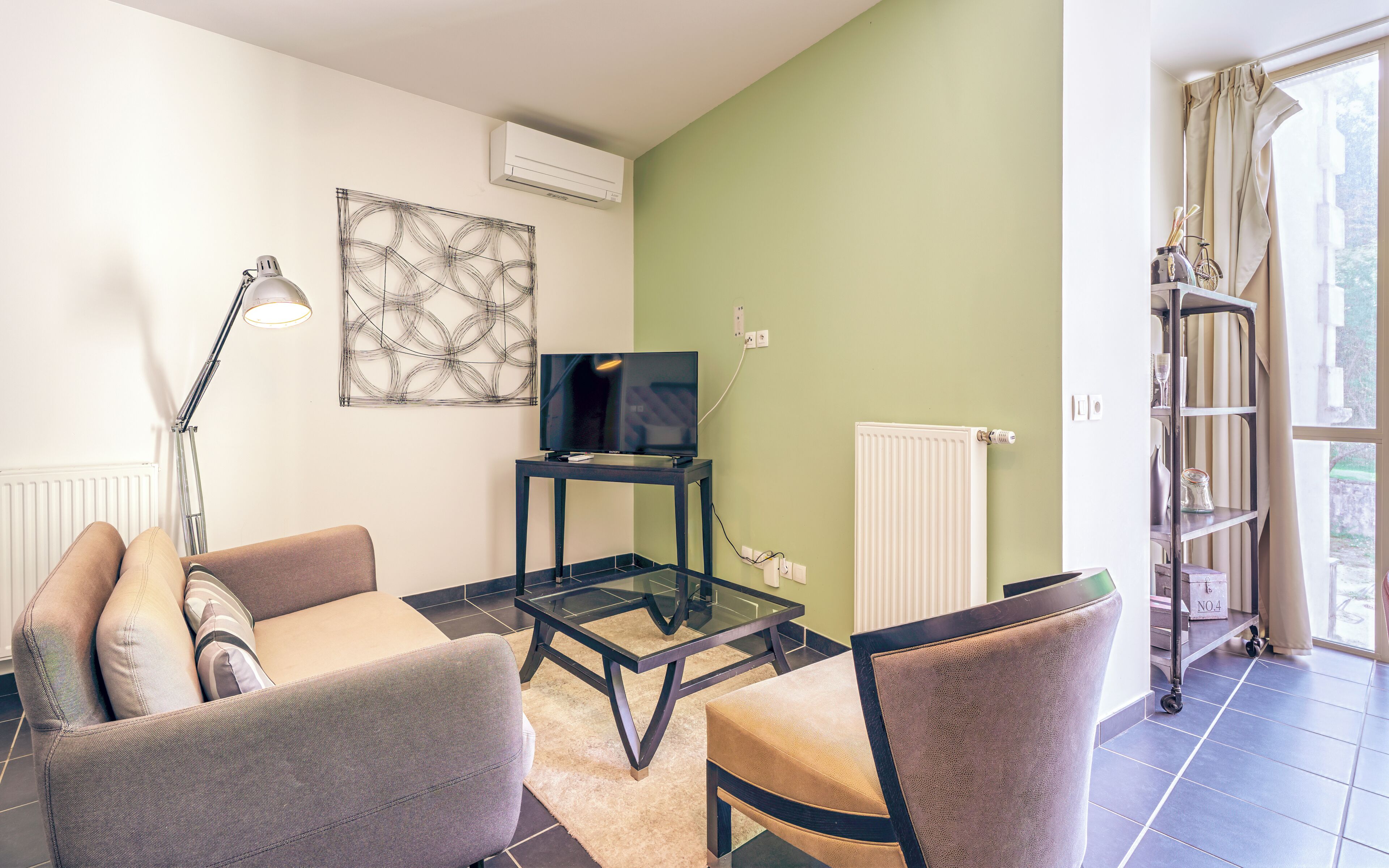 Una sala de estar con sofá, sillón, televisor y una obra de arte en la pared.