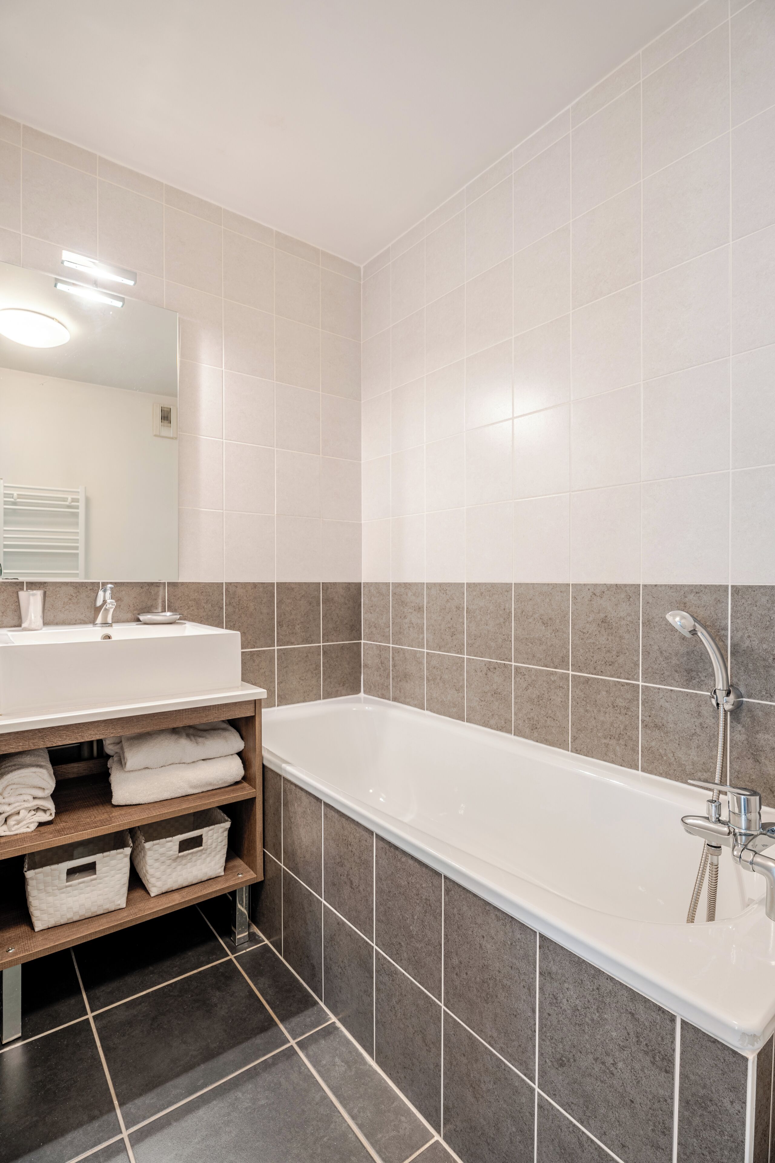 Un baño moderno con un lavamanos blanco, una bañera y un espejo.
